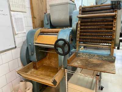 A questo punto la donna ci indica una serie di strumenti che usa quotidianamente, tra cui due impastatrici blu degli anni 60. La prima, in legno, serve a realizzare varie misure di tagliatelle e tagliolini...